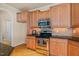 Kitchen showcasing wood cabinets, stainless steel appliances, and black countertops at 5233 Greymoss Ln, Apex, NC 27539