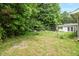 View of backyard with white building in background, green lawn, and lush surrounding trees at 5805 Craig Rd, Durham, NC 27712