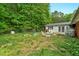 Lush backyard with a mix of open lawn and wooded areas, featuring patio furniture and a fenced perimeter at 5805 Craig Rd, Durham, NC 27712