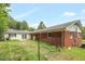 Backyard showcasing brick and white siding, along with a chain-link fence and overgrown vegetation at 5805 Craig Rd, Durham, NC 27712