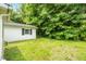 View of backyard with white building, green lawn, lush trees and vegetation at 5805 Craig Rd, Durham, NC 27712