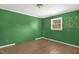 Green bedroom featuring wood-look flooring, and a window at 5805 Craig Rd, Durham, NC 27712