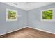 Bedroom with hardwood flooring, light blue walls, and two windows providing natural light at 5805 Craig Rd, Durham, NC 27712