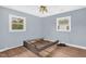 Bedroom with hardwood floors, light blue walls, two windows, and a frame bed at 5805 Craig Rd, Durham, NC 27712