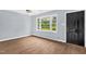Bright bedroom with hardwood floors, a ceiling fan, a large window, and access to the hallway at 5805 Craig Rd, Durham, NC 27712