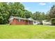 Classic single-story house featuring brick and white accents, a cozy front yard, and mature trees at 5805 Craig Rd, Durham, NC 27712