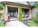 Inviting front porch features stone pillars and comfortable seating with beautiful landscaping at 67 Marshlane Way, Clayton, NC 27527