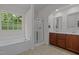 Bright bathroom featuring a soaking tub, glass shower, and double sink vanity with wooden cabinets at 740 Treviso Ln, Apex, NC 27502