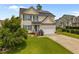 Charming two-story home with a well-manicured lawn, solar panels, and attached garage on a sunny day at 76 Haywood St, Spring Lake, NC 28390