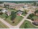 Expansive aerial view of a red brick home surrounded by green lawns and mature trees within a community at 7800 Twin Pines Way, Fuquay Varina, NC 27526