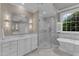 Bright bathroom featuring a soaking tub, a glass shower, and double sinks at 7800 Twin Pines Way, Fuquay Varina, NC 27526