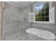The bright bathroom boasts a soaking tub, a glass shower, and open windows at 7800 Twin Pines Way, Fuquay Varina, NC 27526