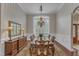 Formal dining room featuring wainscoting, striped walls, chandelier, and ample natural light from a large window at 7800 Twin Pines Way, Fuquay Varina, NC 27526