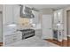 Close-up of kitchen featuring a gas range, white cabinets, and marble backsplash and countertops at 7800 Twin Pines Way, Fuquay Varina, NC 27526