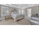 Elegant main bedroom with tray ceiling, a decorative bed, and a view into ensuite bathroom at 7800 Twin Pines Way, Fuquay Varina, NC 27526