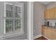 Walk-in pantry featuring wood cabinets with light countertops, and a well-lit window with white shutters at 7800 Twin Pines Way, Fuquay Varina, NC 27526