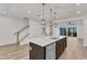 Open-concept kitchen with a large island, stainless steel appliances, hardwood floors, and access to the stairwell at 816 Lilyquist Way, Wake Forest, NC 27587
