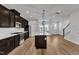 Open-concept kitchen features a central island, dark wood cabinetry, stainless steel appliances, and hardwood flooring at 816 Lilyquist Way, Wake Forest, NC 27587