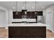 Bright kitchen with a large island, dark wood cabinetry, stainless steel appliances and hardware, and white backsplash at 816 Lilyquist Way, Wake Forest, NC 27587