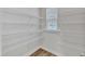 Walk-in closet with white wire shelving, a window for natural light, and wood flooring at 816 Lilyquist Way, Wake Forest, NC 27587