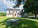 Exterior shot of the back of the home with green grass, trees, and chicken coop at 8365 Aaron Creek Church Rd, Oxford, NC 27565
