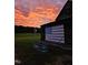 Rustic barn displays a historic American flag under a dramatic sunset sky, symbolizing Americana heritage at 8365 Aaron Creek Church Rd, Oxford, NC 27565