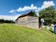 Rustic barn featuring weathered wood, sliding door, and decorative windmill in the yard at 8365 Aaron Creek Church Rd, Oxford, NC 27565