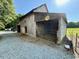 Rustic barn featuring open bay, gravel driveway, and adjacent fenced garden area at 8365 Aaron Creek Church Rd, Oxford, NC 27565