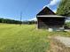 An old barn stands in a lush, green field under a bright, blue sky at 8365 Aaron Creek Church Rd, Oxford, NC 27565