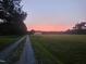 Gravel driveway leading to a picturesque property amidst a serene landscape in the early evening at 8365 Aaron Creek Church Rd, Oxford, NC 27565