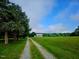 Scenic driveway view of the two-story farmhouse nestled on sprawling acreage at 8365 Aaron Creek Church Rd, Oxford, NC 27565