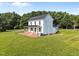Rear view of the white two-story home on a lush green lawn with mature trees at 8365 Aaron Creek Church Rd, Oxford, NC 27565