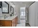 Bright bathroom featuring double sinks, wood cabinets and view into the primary bedroom at 8404 Saltwood Pl, Raleigh, NC 27617