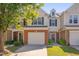 Inviting townhome exterior with a brick facade, attached garage, and lush green lawn at 8404 Saltwood Pl, Raleigh, NC 27617