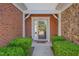 Home's entryway features a charming brick surround, pristine glass door, and manicured bushes at 8404 Saltwood Pl, Raleigh, NC 27617
