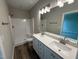 Bathroom with double sink vanity, bright lights, shower, and hardwood style flooring at 90 Brookhaven Dr, Spring Hope, NC 27882