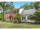 Charming two-story home featuring a brick facade, white siding, black shutters, and a well-maintained landscaped yard at 9509 Greenfield Dr, Raleigh, NC 27615