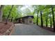 Stunning exterior elevation of modern home featuring walls of glass, brick entryway, and gravel driveway surrounded by lush forest at 1 Davie Ln, Chapel Hill, NC 27514
