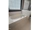 White soaking tub is brightened by natural light filtering through window blinds at 1017 Red Hat Ln, Durham, NC 27713