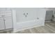 Bathroom featuring a white tiled bathtub, gray cabinets, and wood-look vinyl flooring at 106 E Club Blvd, Durham, NC 27704