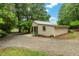 Home with metal roof featuring a gravel driveway surrounded by mature landscaping at 1085 Bynum Rd, Pittsboro, NC 27312