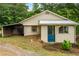 Charming single-story home with a blue front door and a covered carport nestled in a wooded setting at 1085 Bynum Rd, Pittsboro, NC 27312