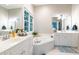 Bright bathroom with dual sinks, white cabinets, garden tub, large window, and blue rug at 116 Hamilton Hedge Pl, Cary, NC 27519
