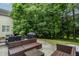 Back patio with stone ground, well-manicured lawn, grill, and surrounding trees at 116 Hamilton Hedge Pl, Cary, NC 27519