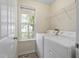 Functional laundry room featuring a window, machines, and neutral paint colors at 118 Setter Pt, Clayton, NC 27520