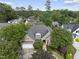 Aerial view of brick home with a two-car garage surrounded by mature trees, lush landscaping, and a gray roof at 1210 Brooks Ave, Raleigh, NC 27607