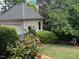 Backyard view with a detached garage, surrounded by lush landscaping and greenery for privacy at 1210 Brooks Ave, Raleigh, NC 27607