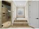 Luxurious bathroom featuring a tiled shower, soaking tub with tile surround, and a door at 1210 Brooks Ave, Raleigh, NC 27607