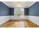 Dining area with hardwood floors, blue accent wall, wainscoting, white trim and window with plantation shutters at 1210 Brooks Ave, Raleigh, NC 27607