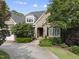 Charming brick home featuring an arched entryway, lush landscaping, and a spacious driveway with a side entry garage at 1210 Brooks Ave, Raleigh, NC 27607